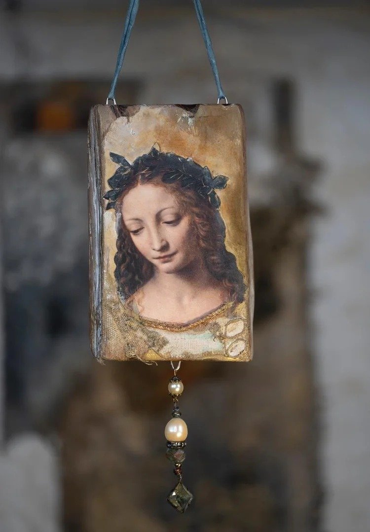 Hanging religious icon depicting a woman with a crown of thorns, with pearl and bead decorations below.