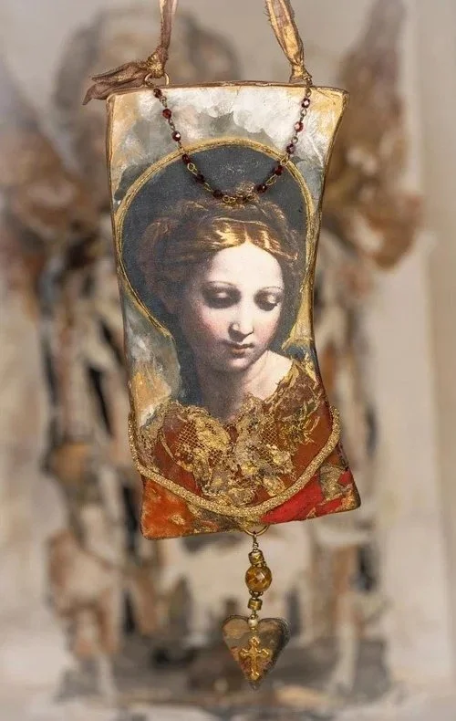 Hanging religious icon depicting a woman with a halo, framed in gold, with a necklace and a heart-shaped pendant attached.