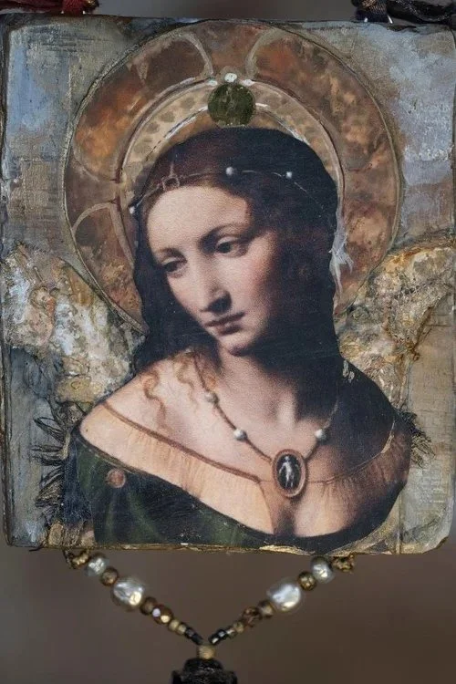 A religious icon depicting the Virgin Mary with a halo, wearing jewelry, and a necklace with a pendant, set against a textured background.