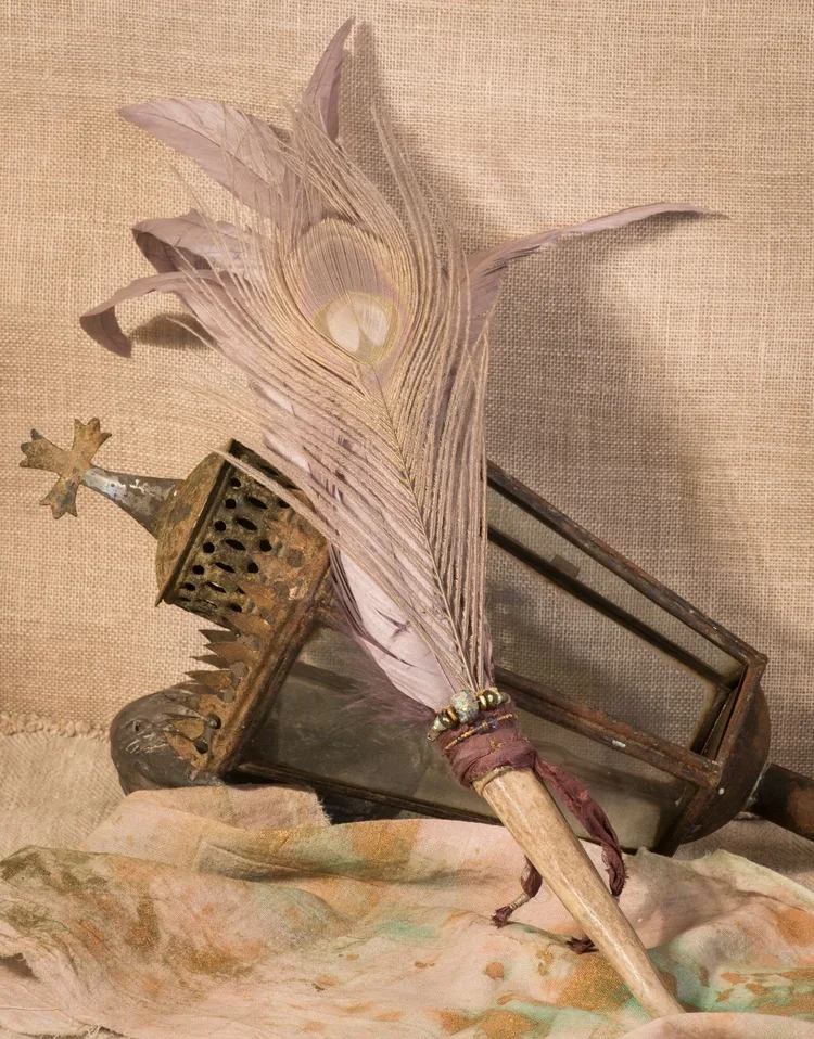 A decorative feathered prop with beads, an old lantern, and cloth with floral patterns.