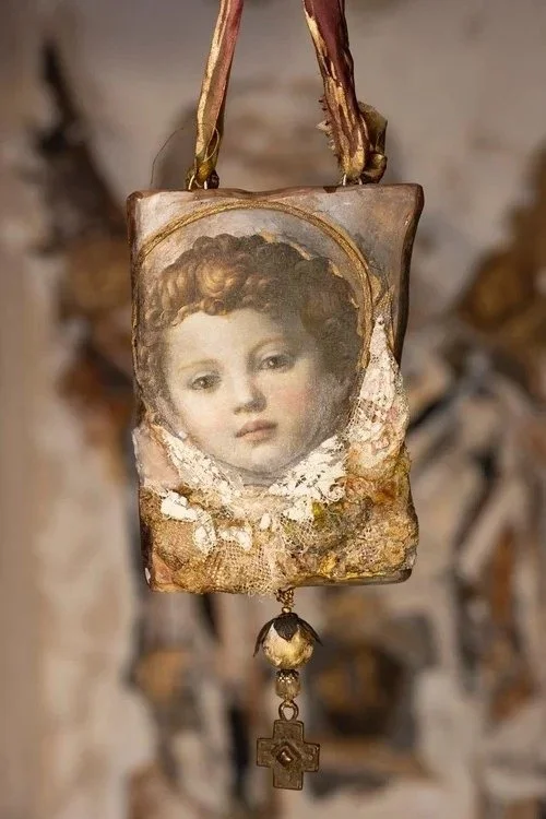 A vintage necklace with a portrait of a young girl and a small cross pendant hanging below.
