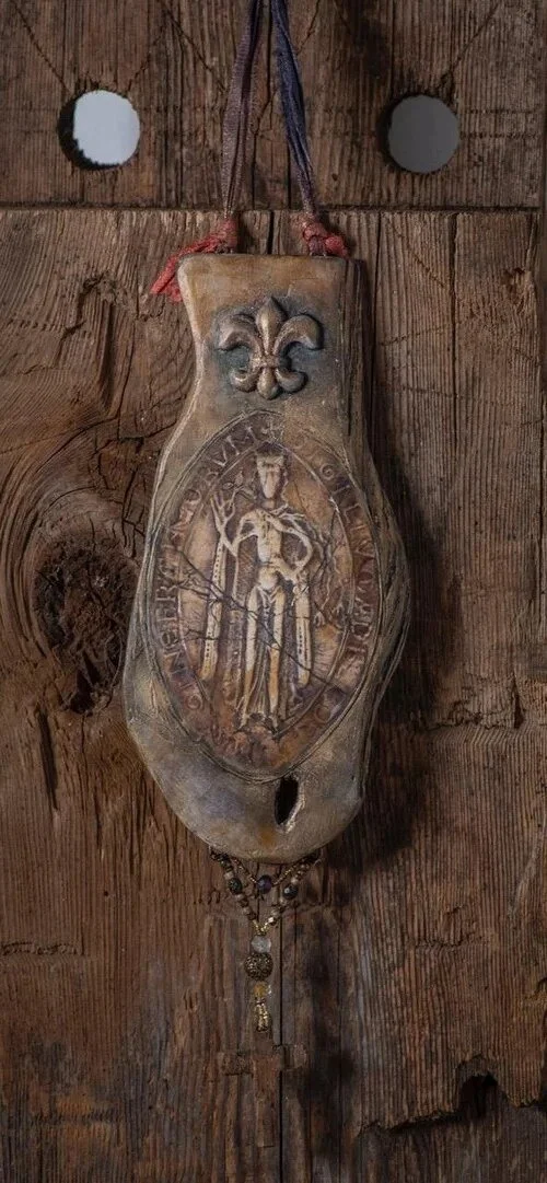 An ornate antique wooden religious artifact hanging on a rustic wooden wall.