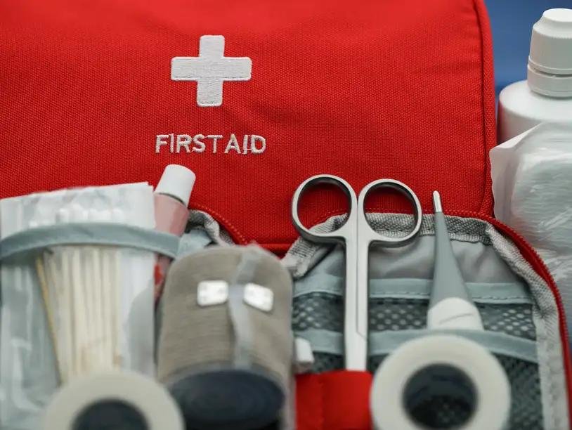 First aid kit with medical supplies, including scissors, tweezers, tape, and medications.