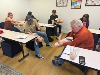 Group of people participating in a team-building activity in a classroom or meeting room.