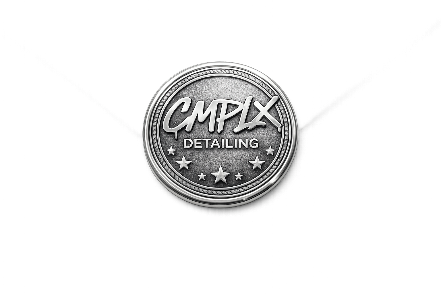 A close-up of a circular metal emblem with the words 'CMPLX DETAILING' and stars around the edge.