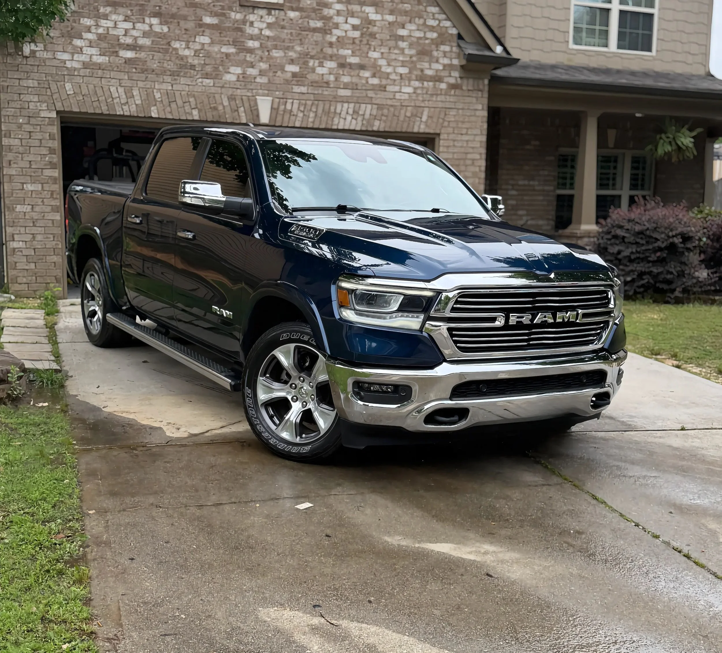 Black RAM truck parked in a residential driveway in front of a brick house.
