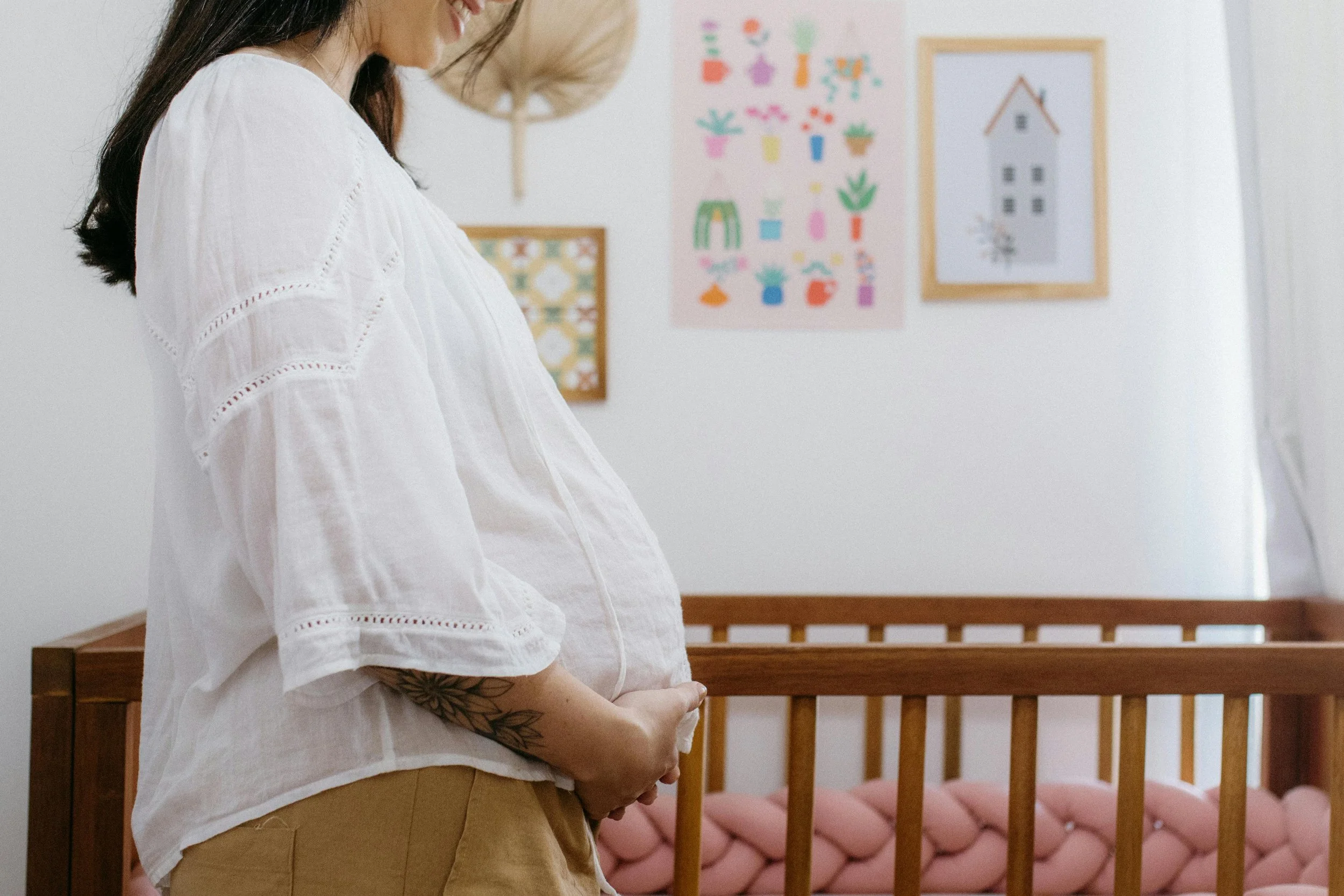 pregnant woman smiling and holding her belly in baby's nursery