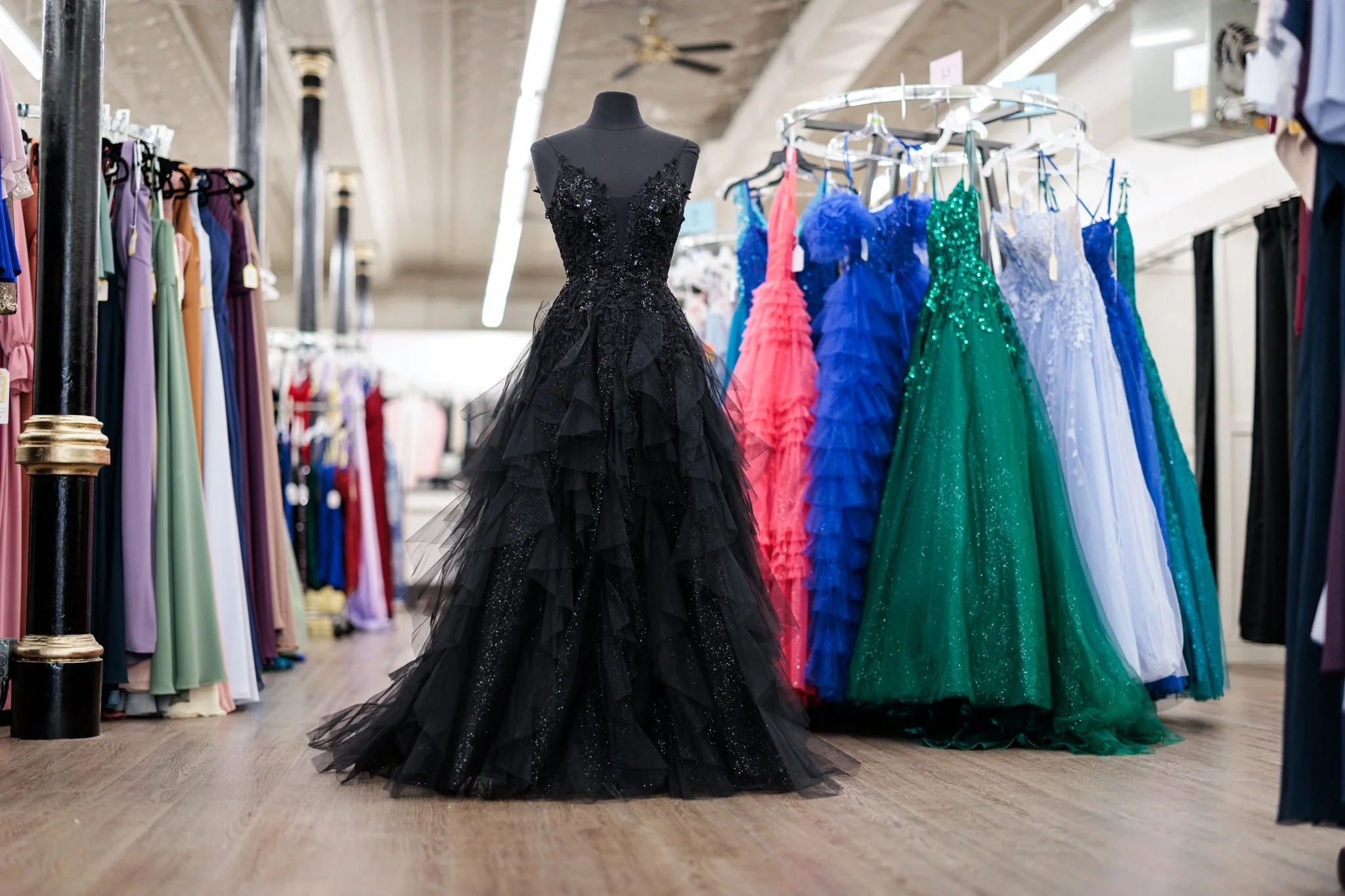 Black dress with tulle layers on a mannequin at a dress store.