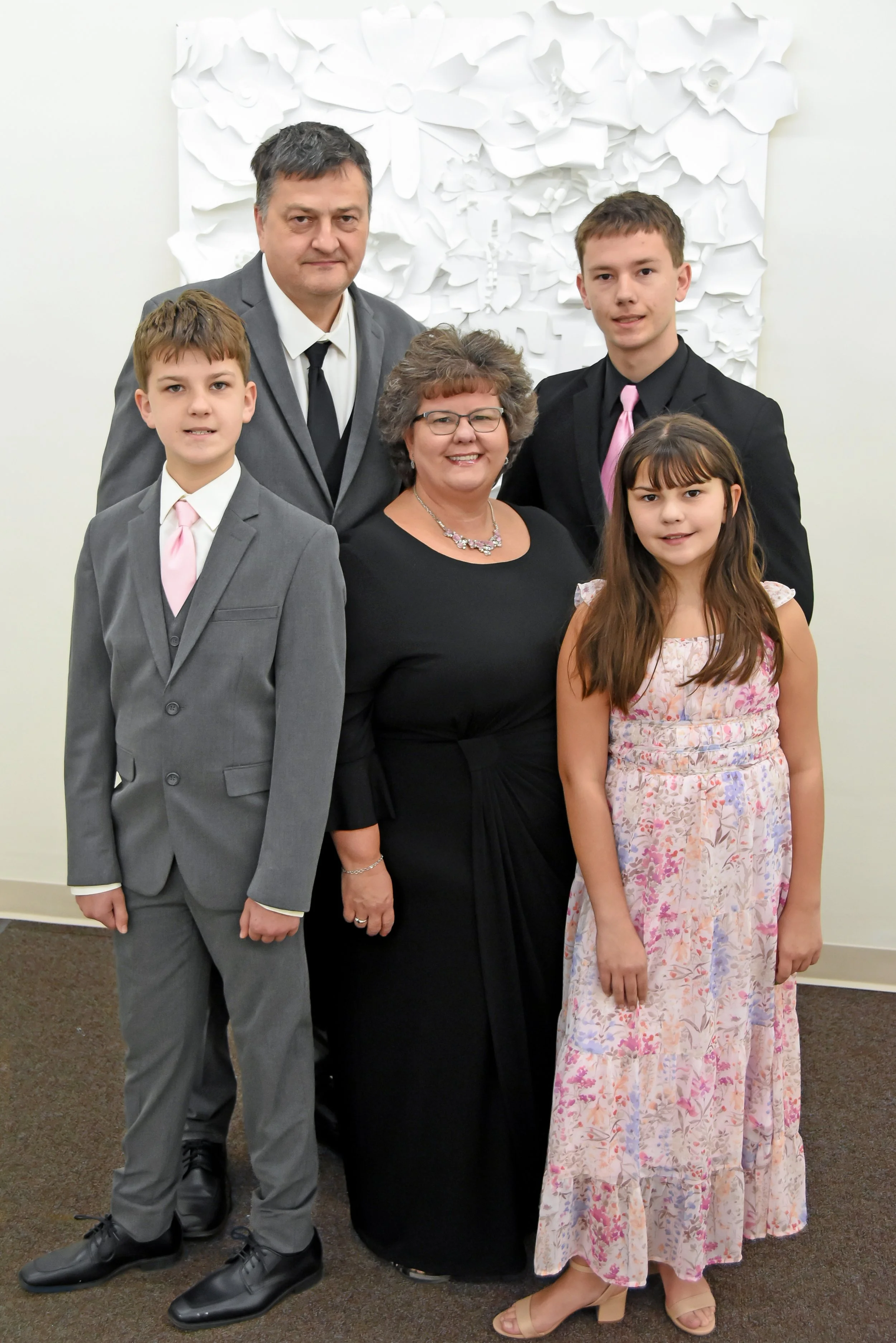 Family of two adults and three children posed wearing suits and formal dresses inside of a room