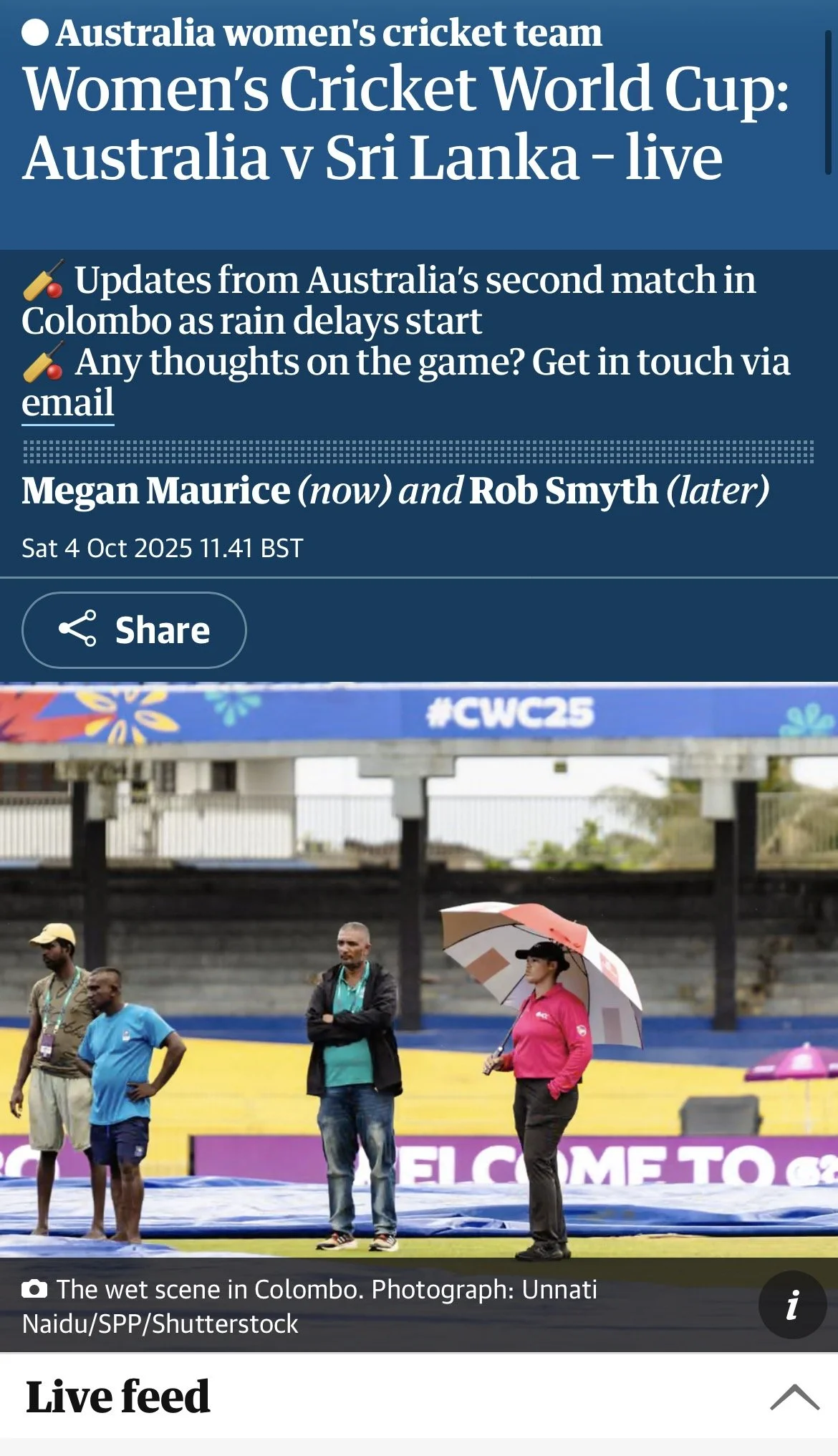 This is a photo of people standing on a sports field in Colombo, Sri Lanka, under rainy weather. Some individuals are holding umbrellas, and there is a large sign in the background that reads "WELCOME TO" with additional text that is partially obscur