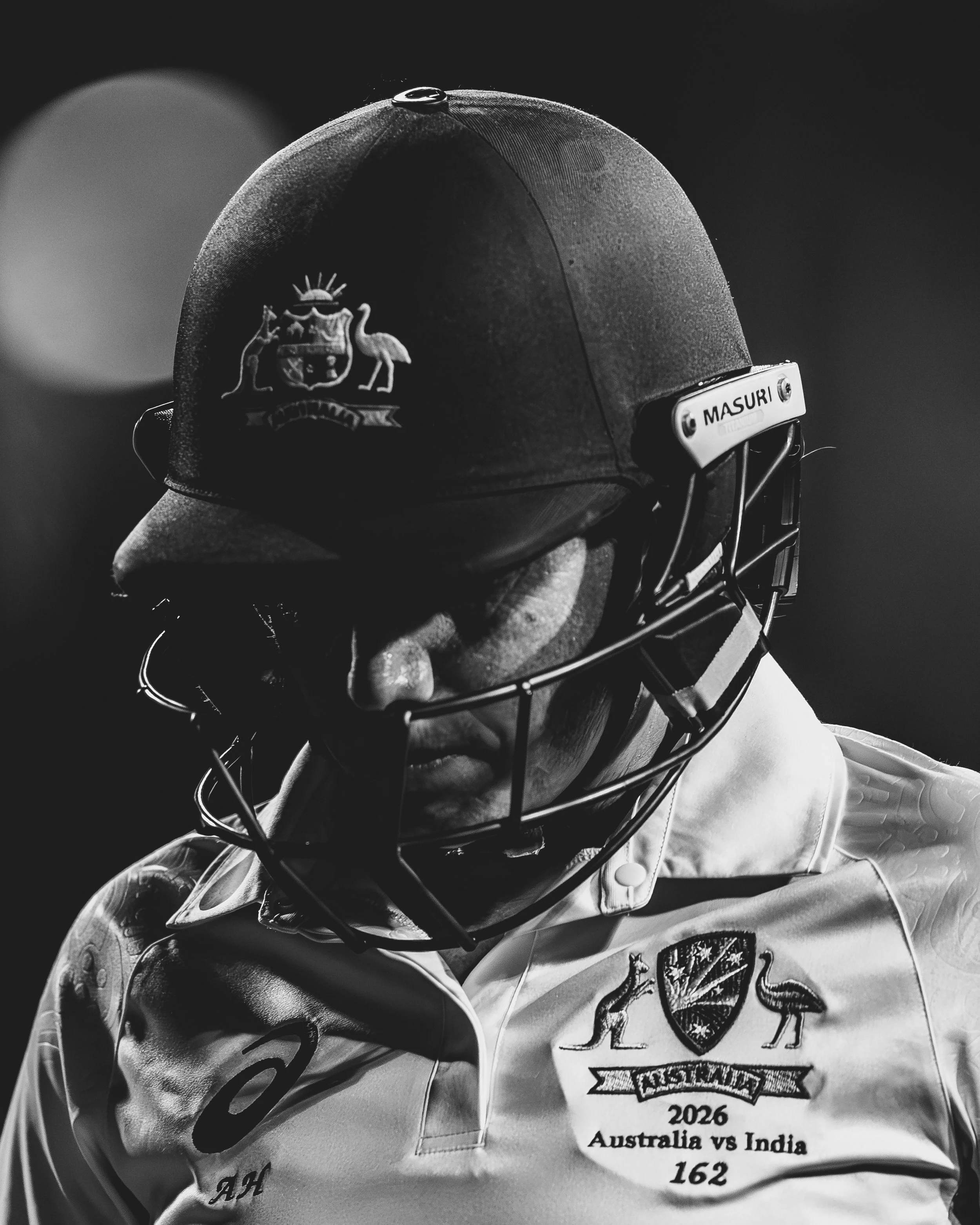 Black and white image of a cricket helmet and jersey with Australian republic emblem, featuring a kangaroo and emu, and text indicating the 2026 Australia vs India cricket match, with a score of 162.