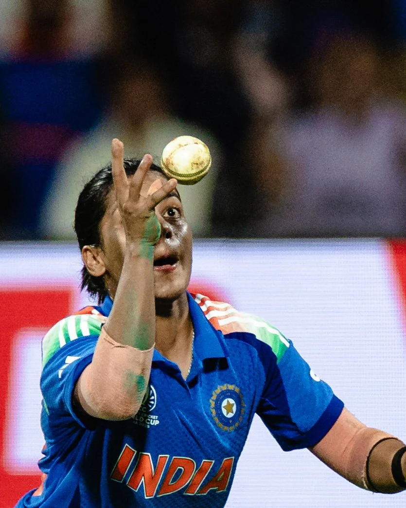 Indian cricket player in blue uniform catching a cricket ball during a game.