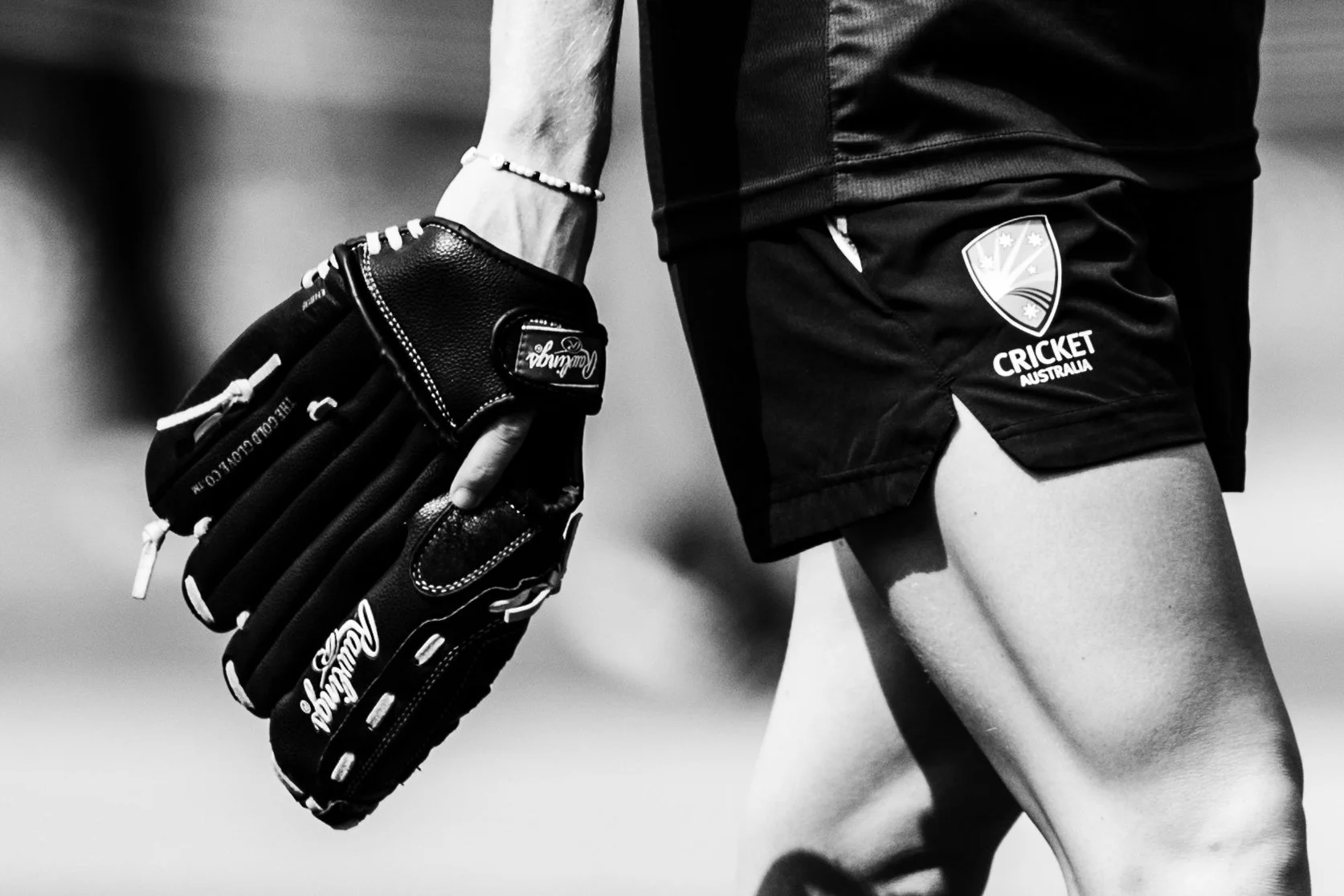 Close-up of a cricket player in uniform, holding a glove, with a focus on shorts bearing the Cricket Australia logo.