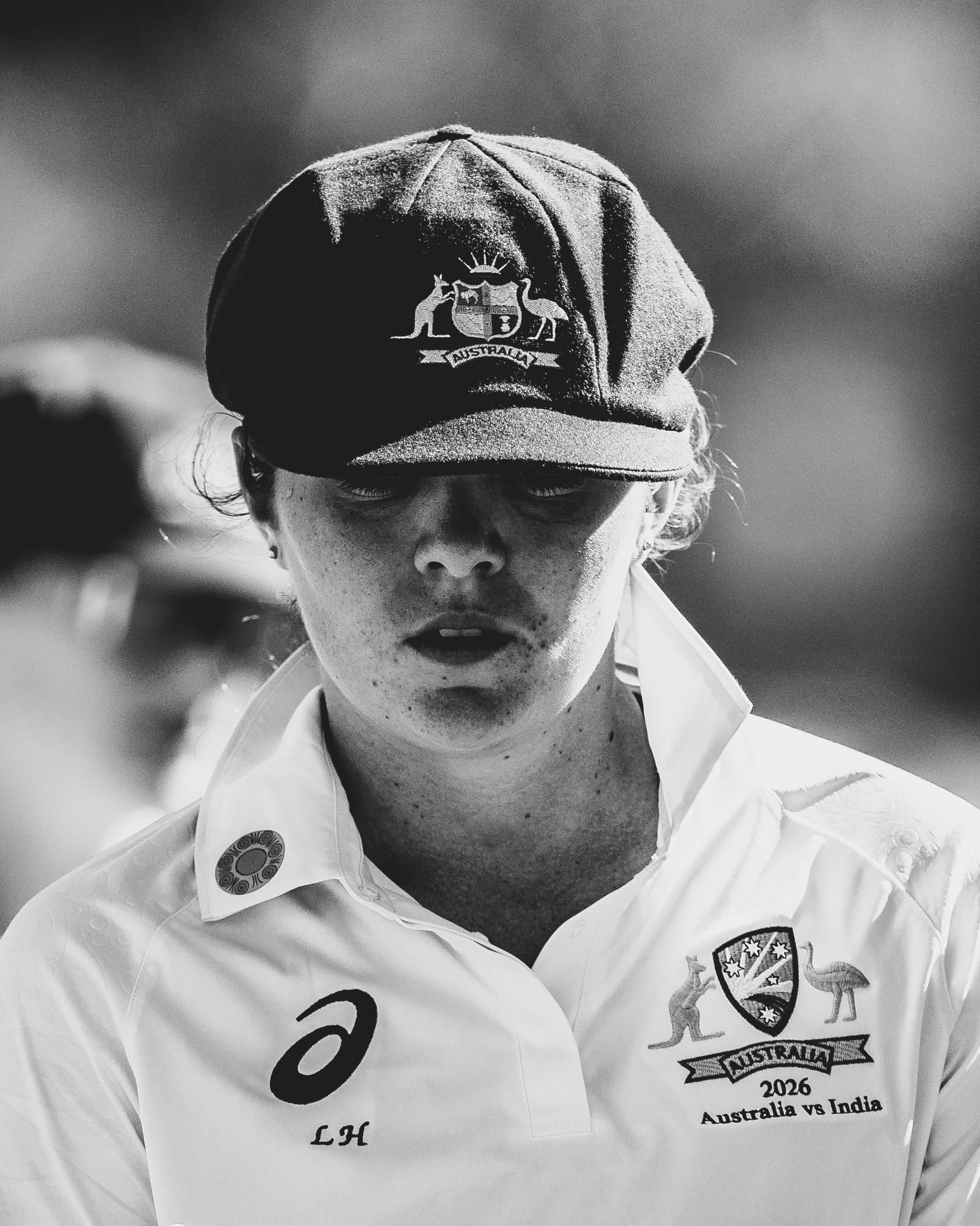 A person wearing a cap and a white jacket with the Australian cricket team logo, participating in a cricket match between Australia and India in 2006.