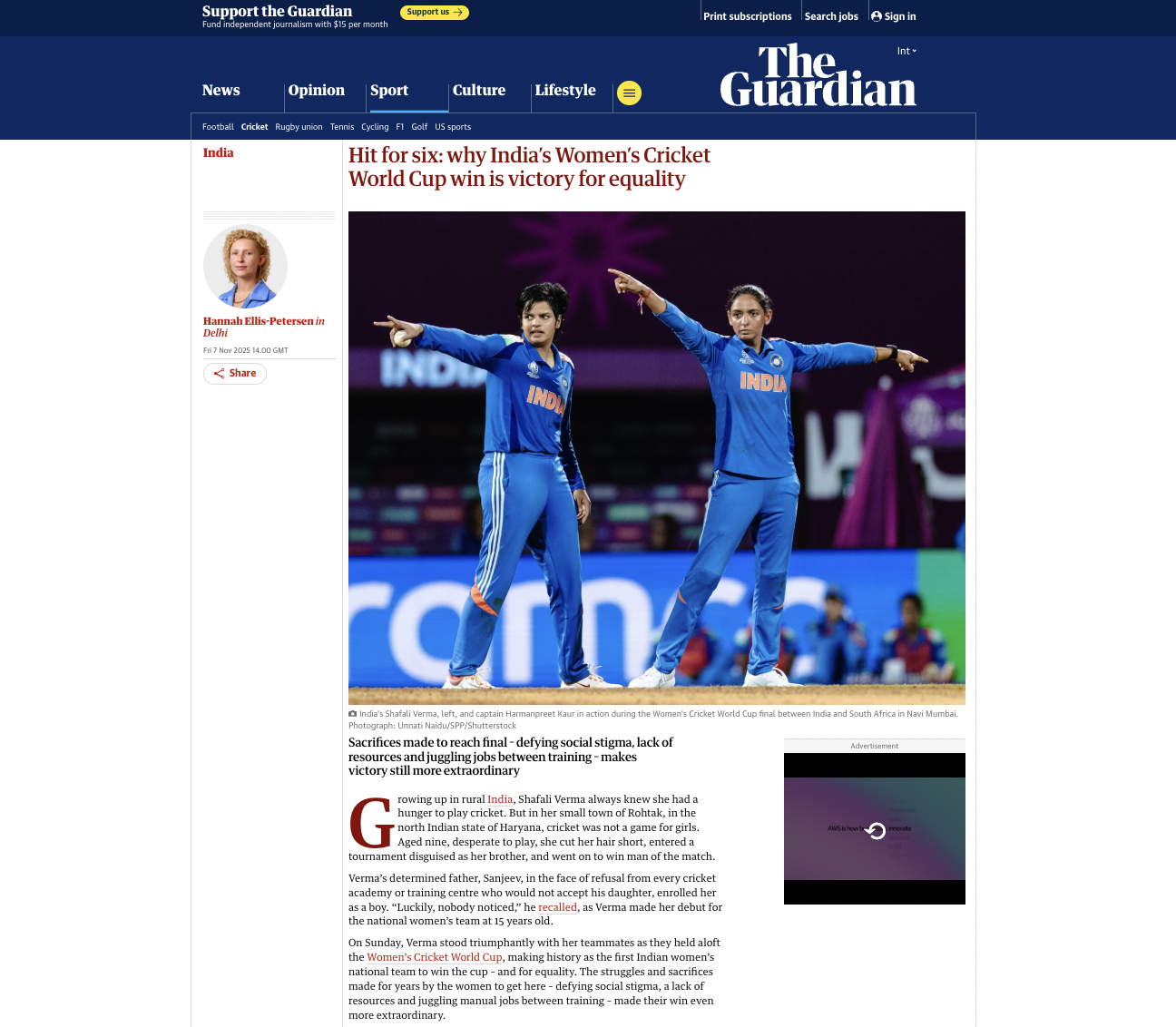 Two Indian women cricket players in blue uniforms standing on the cricket field, one with her right arm extended to the side and the other with her left arm extended to the side, during a match at the Women's Cricket World Cup in Navi Mumbai, India.