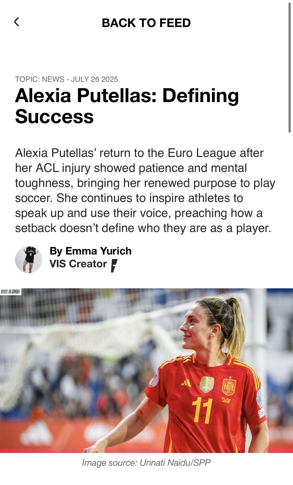 A woman in a red Spain national soccer team jersey with the number 11, smiling and on a soccer field.