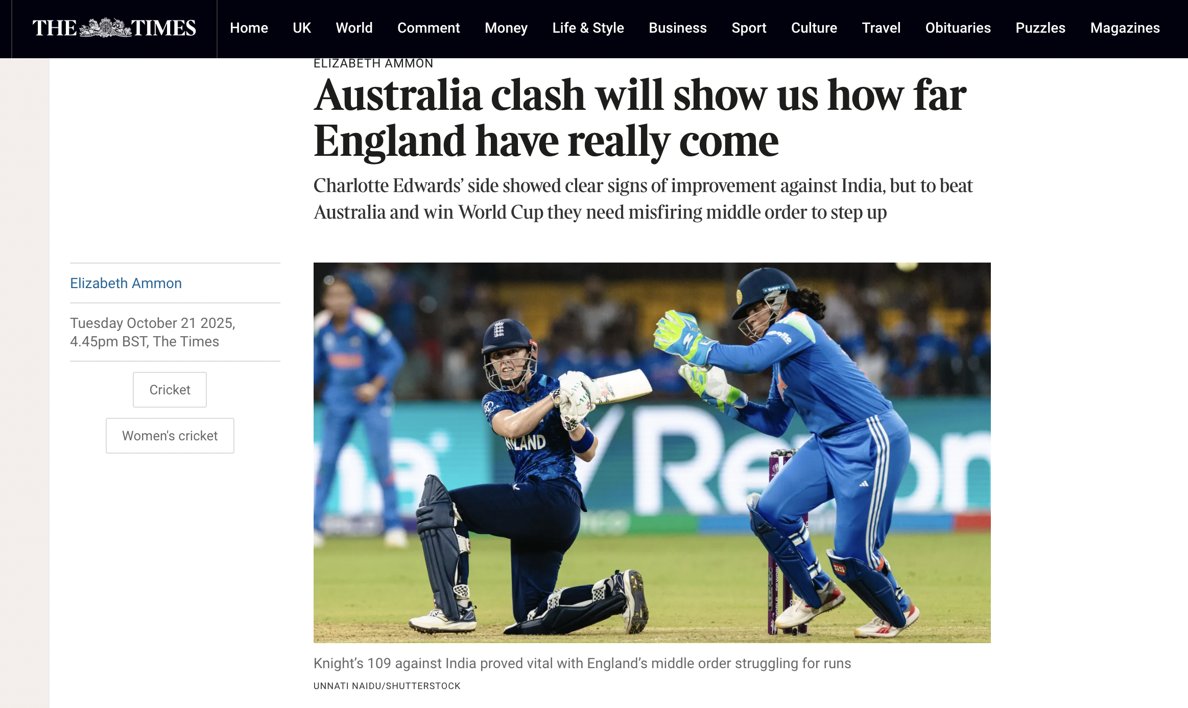 England cricket player in a blue kit kneeling on the ground with a wicketkeeper standing nearby during a match, with a blurred background of a cricket stadium.