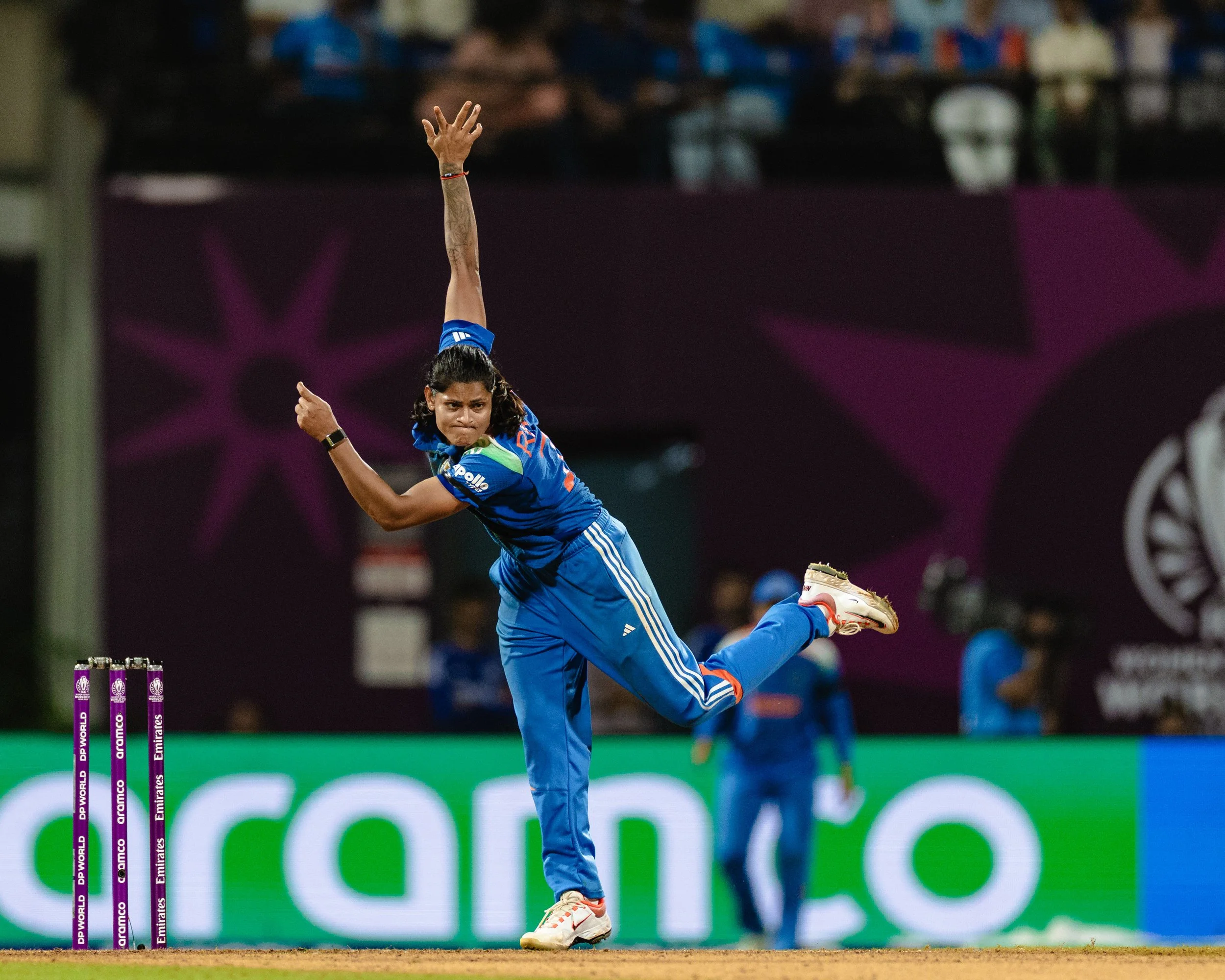Cricketer in blue uniform celebrating a wicket with target stumps in the background.