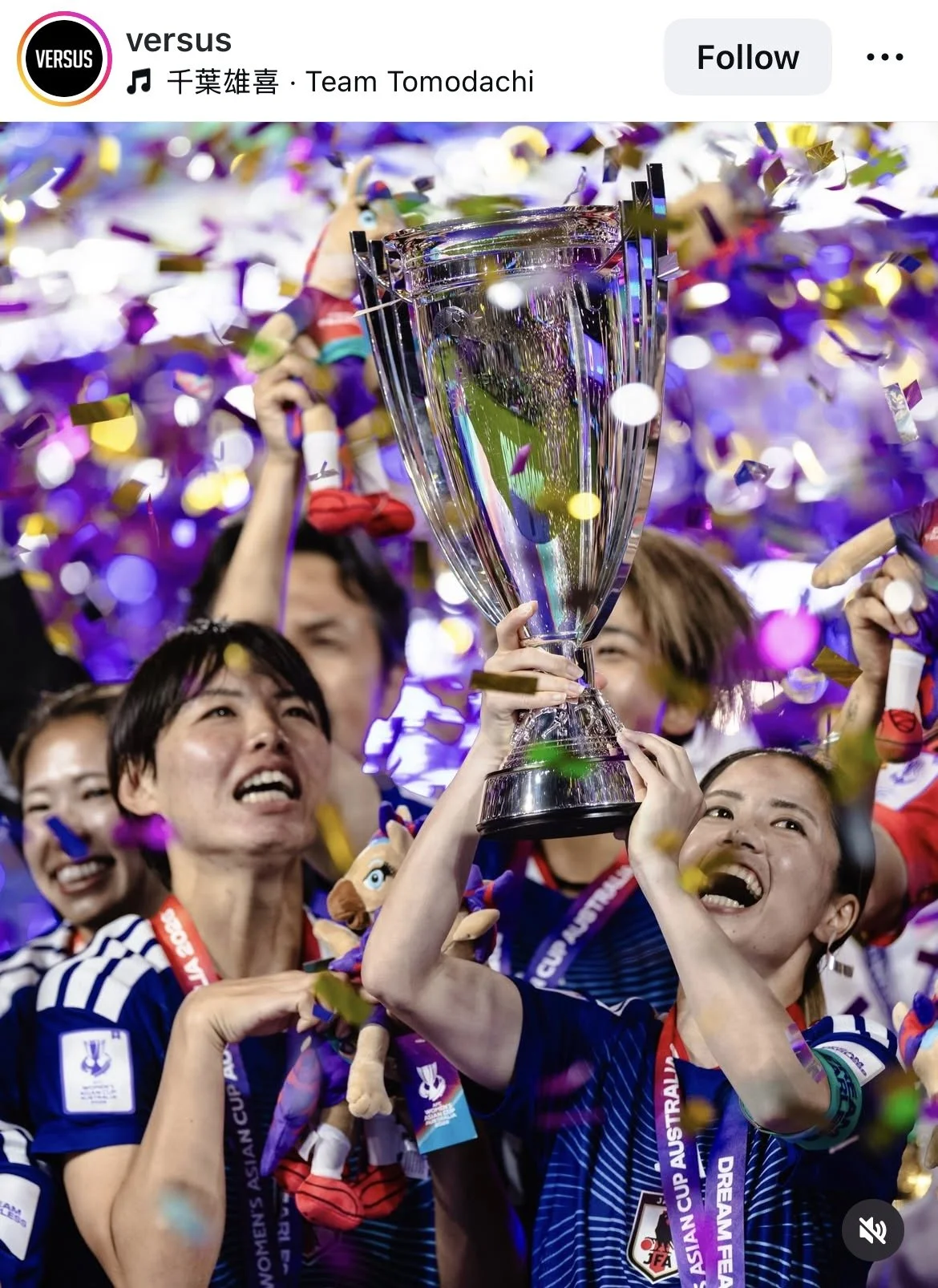 Women’s soccer team celebrating victory, holding a large trophy with confetti falling around them, team members smiling and cheering.