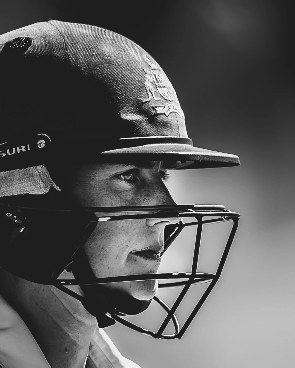 A close-up side profile of an American football player wearing a helmet and faceguard, focused and looking intently forward.