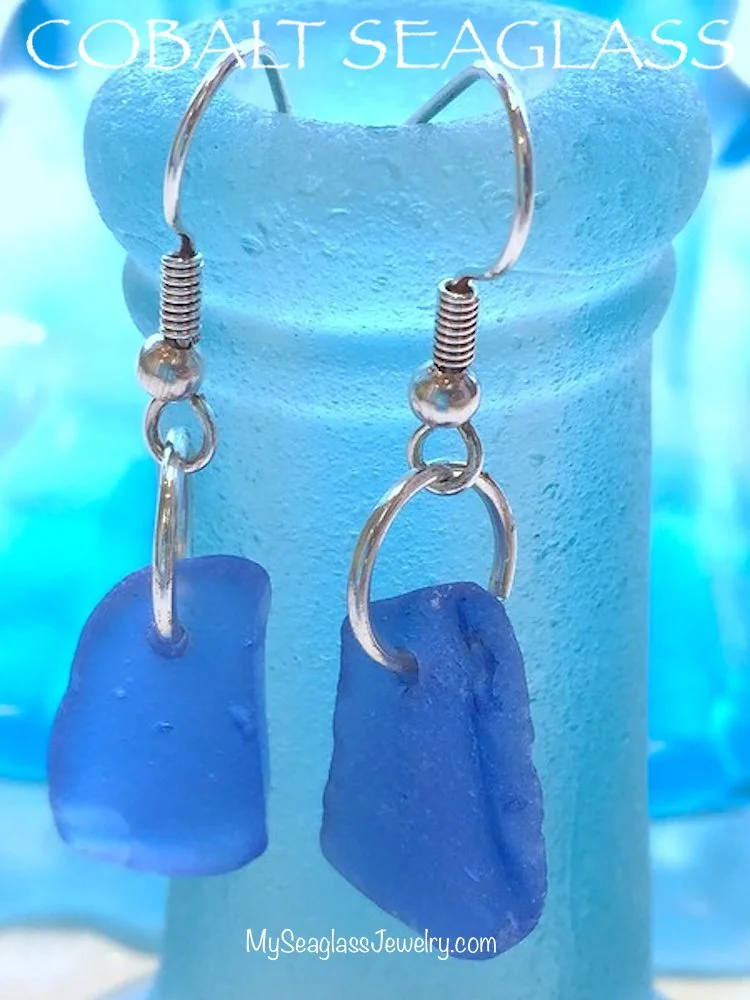 Blue sea glass earrings hanging from a display stand, with the text 'COBALT SEAGLASS' at the top and 'MySeaglassJewelry.com' at the bottom.