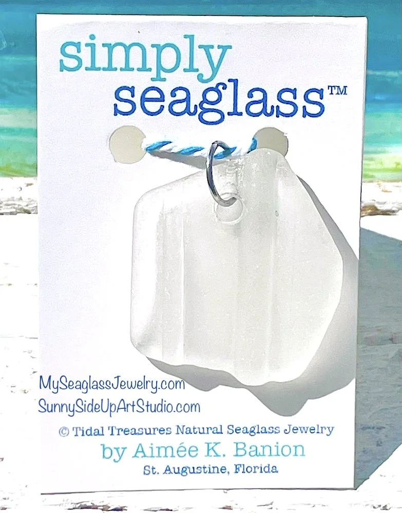 Seaglass jewelry pendant hanging from a blue and white braided cord, with text about seaglass jewelry and artist's information on a white background