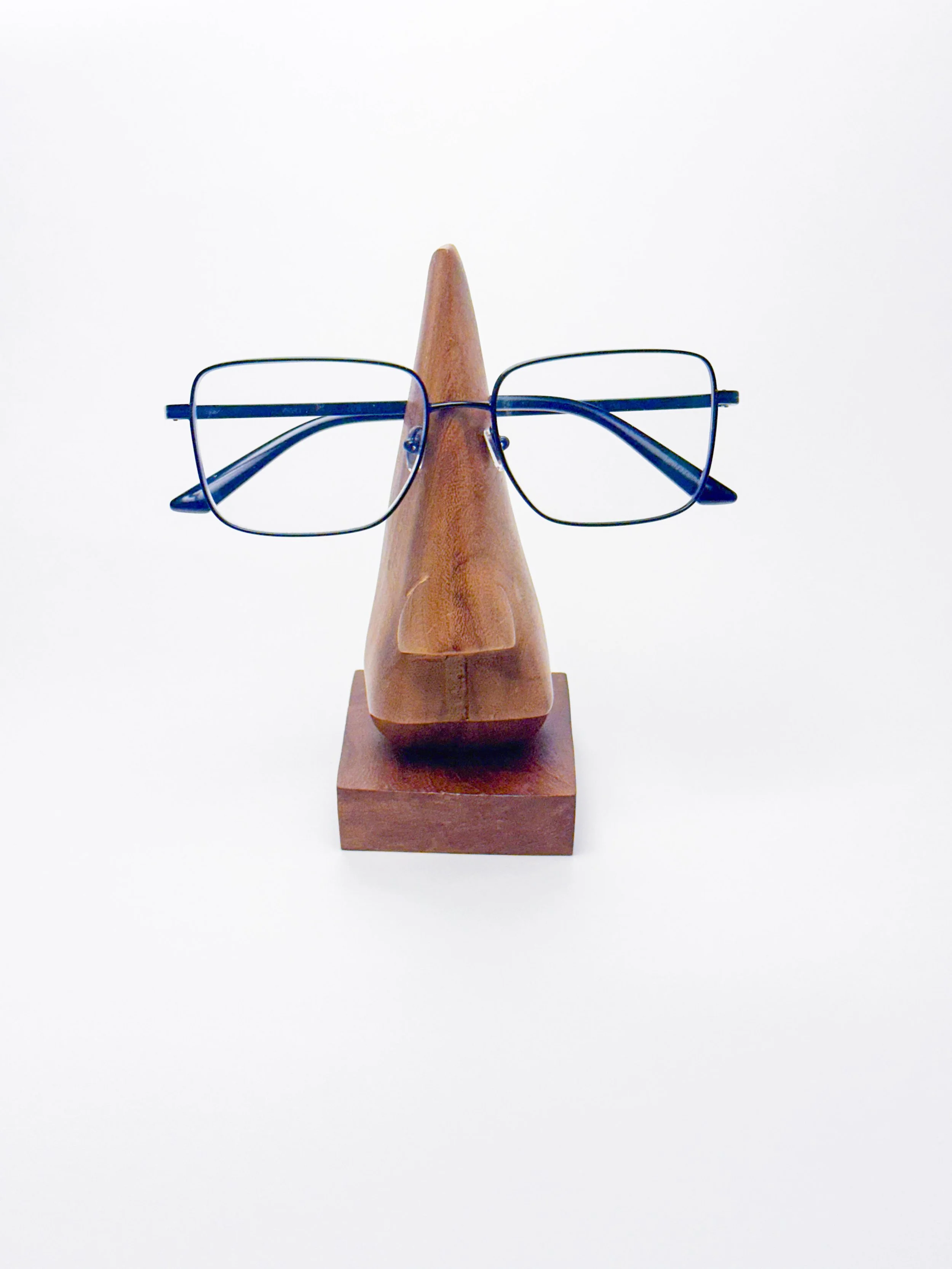 Image of a wooden nose glasses holder with a pair of reading glasses taken on 3/22/2026. This photo is  as part of light box photo assignment capturing the clean details of the items.