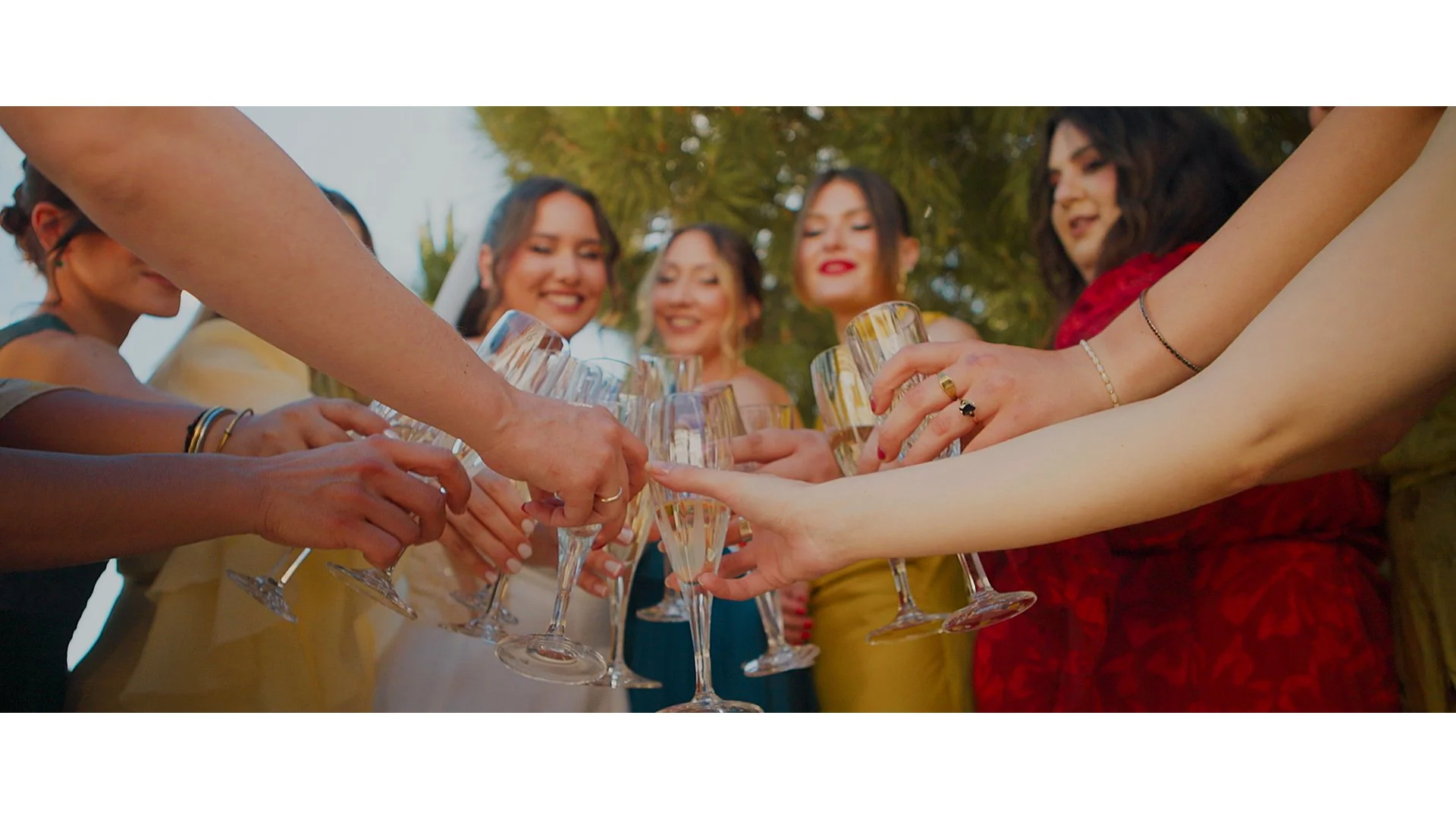 Women clinking champagne glasses outdoors at a celebration or gathering.