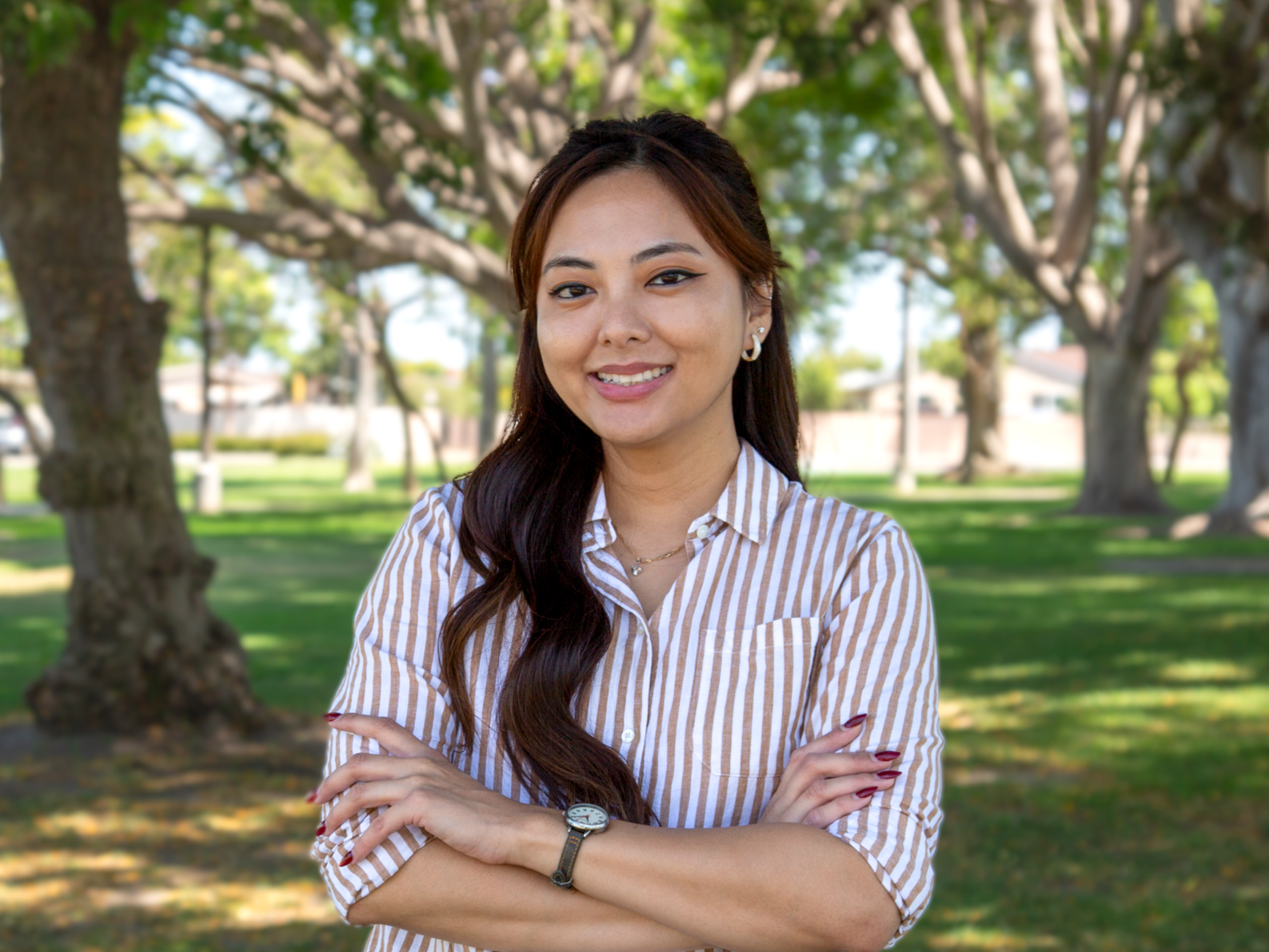 Tracy La stands in the shade of trees in a park.