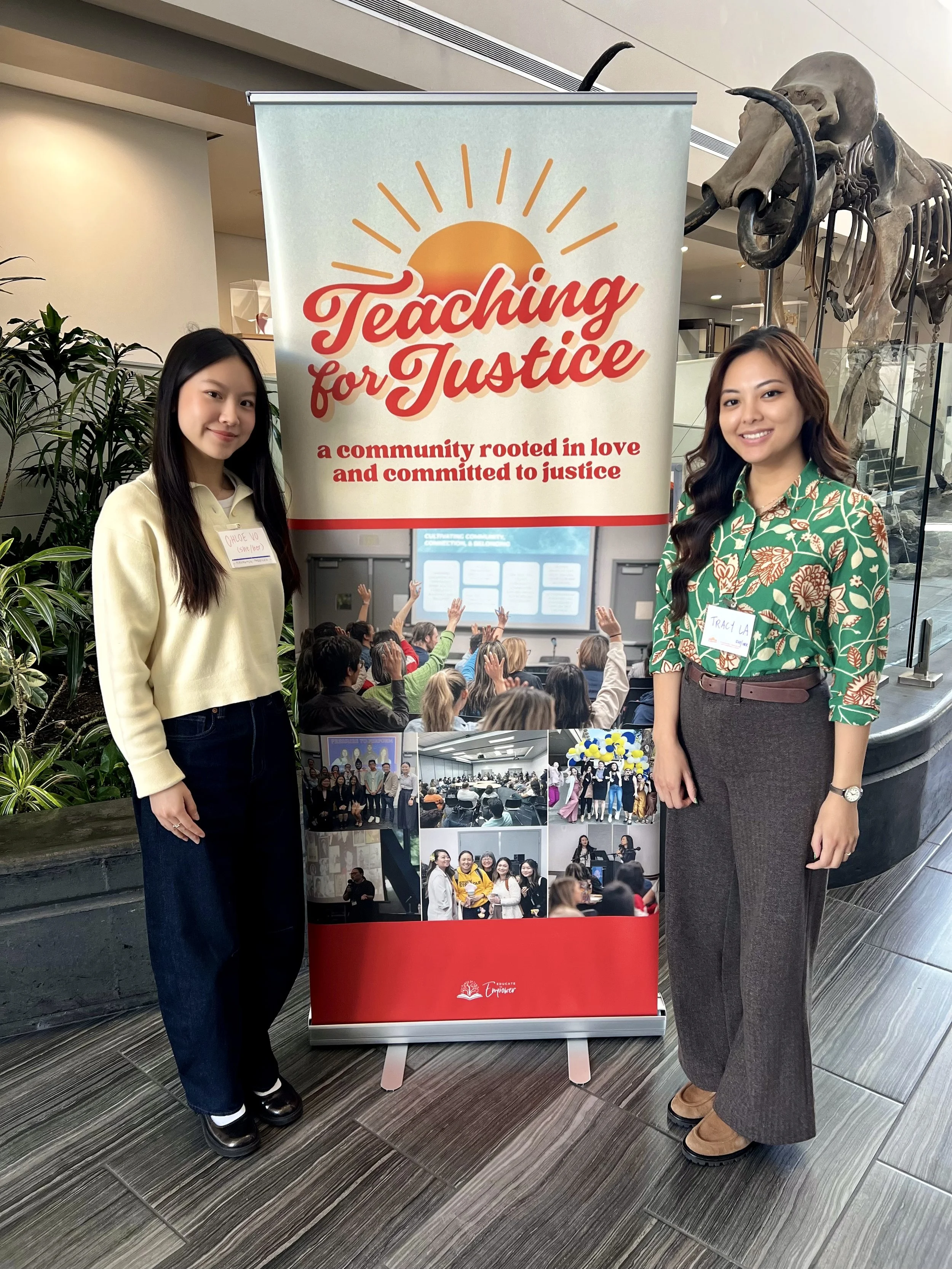 Tracy La stands next to a vertical banner that reads 'Teaching for Justice' with a sun image and a tagline about community and love. Tracy is wearing a green floral blouse.
