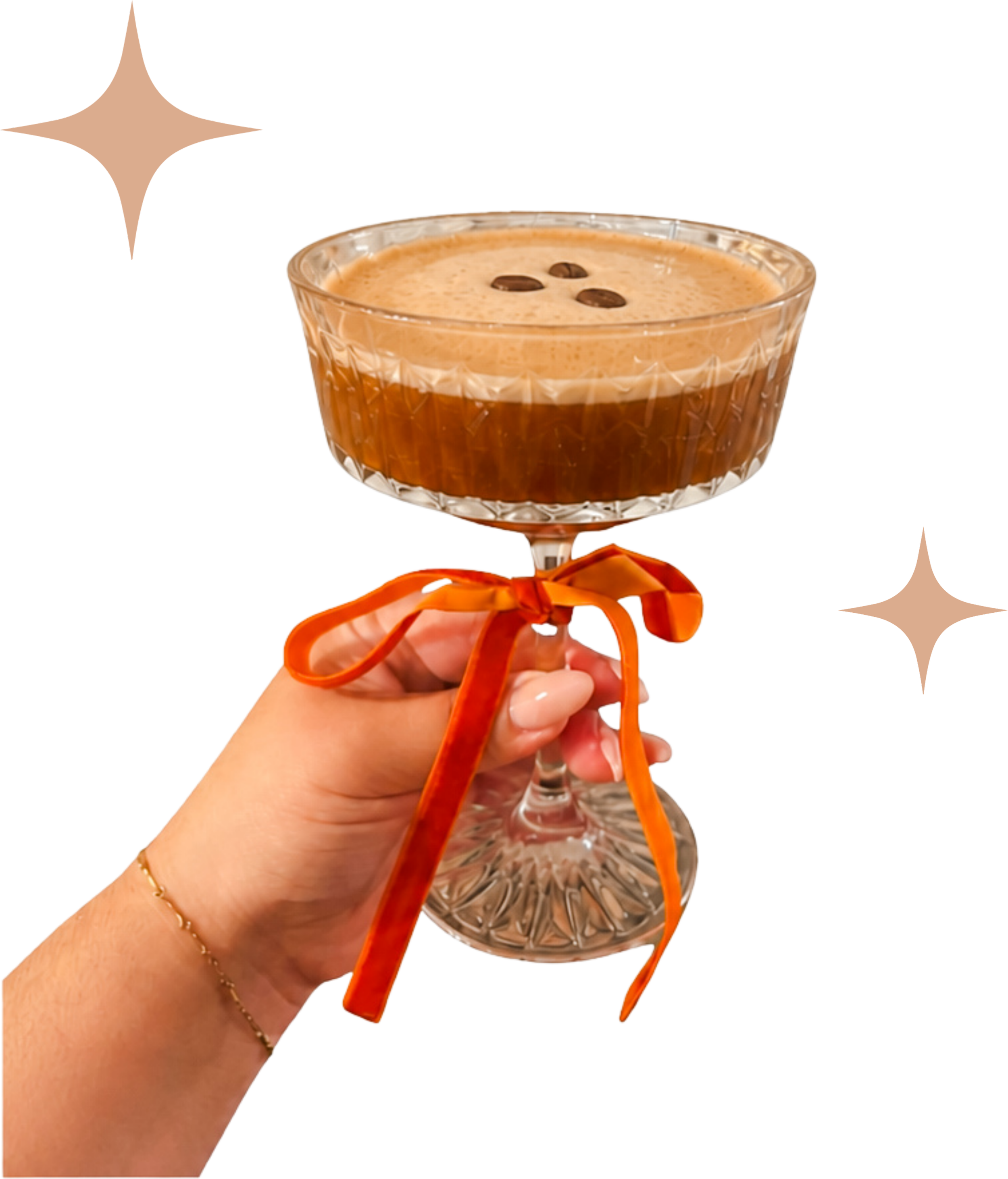 A hand holding a vintage glass champagne coupe with an espresso martini topped with coffee beans, and an orange ribbon tied around the stem.