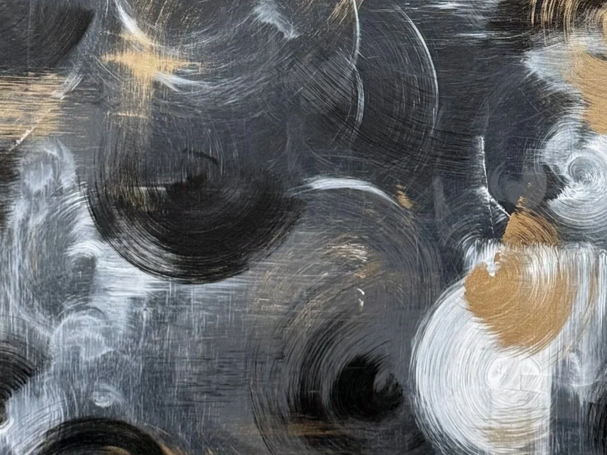 Abstract painting with black, white, and gold circular brushstrokes.