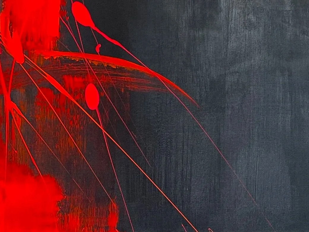Close-up image of red paint splashes and streaks on a dark textured background.