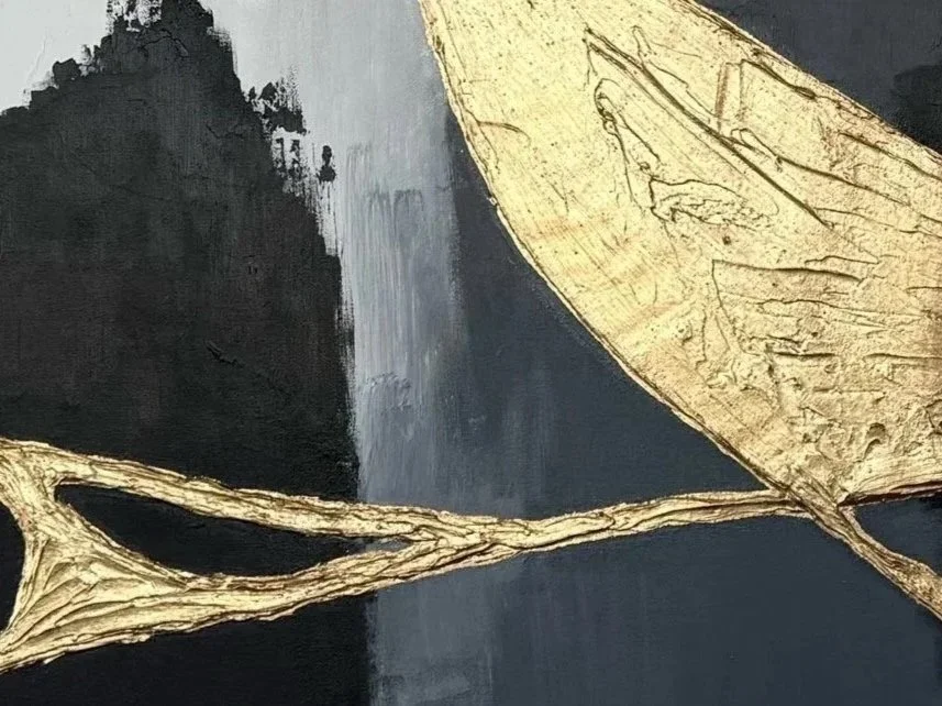 Close-up of a textured black and gray abstract painting with gold leaf accents in leaf and branch shapes.