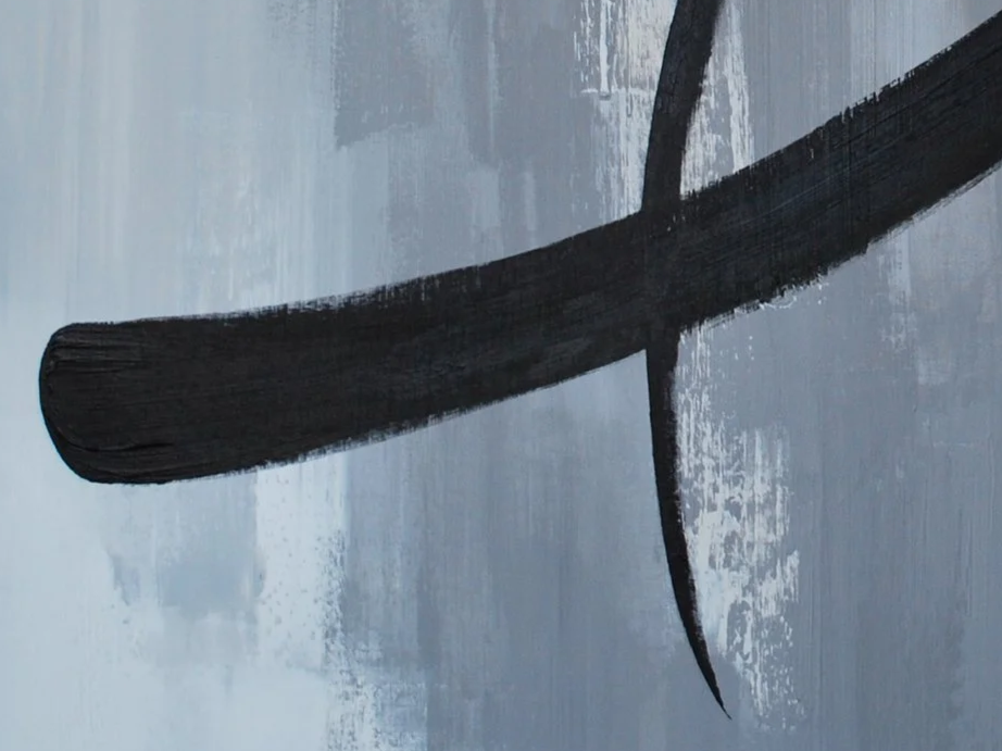 Close-up of a black brushstroke on a grey textured surface.