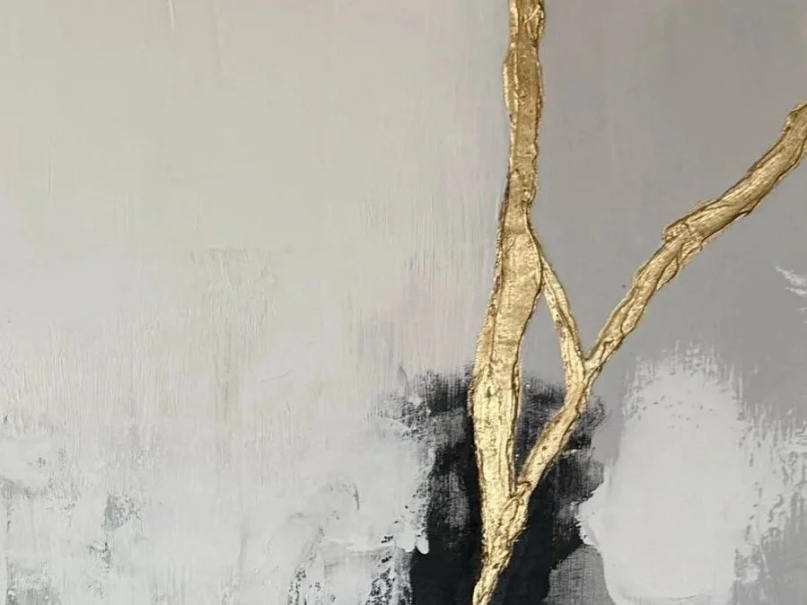 Close-up of a modern wall with an abstract design featuring a vertical gold textured branch-like element against a gray and white background.