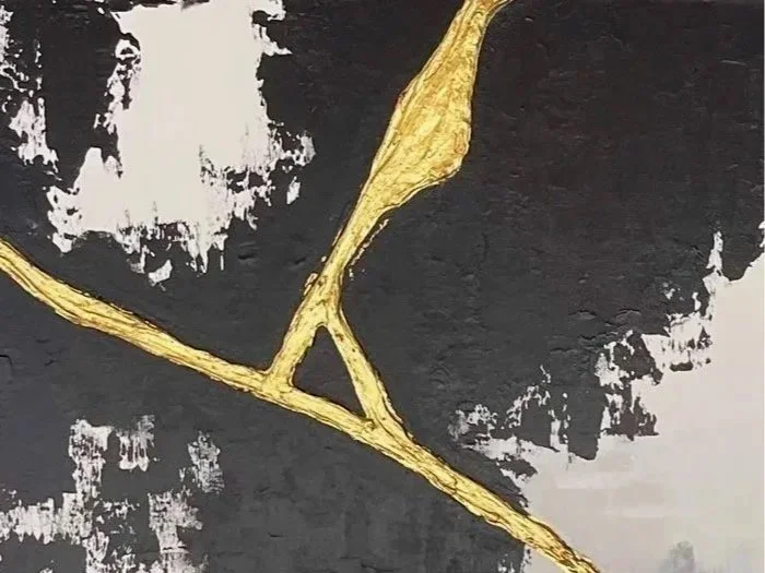 Close-up of a modern abstract painting with black, white, and gold elements.