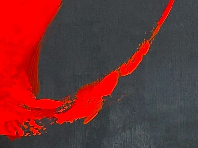 Close-up of black surface with bright red paint streak.