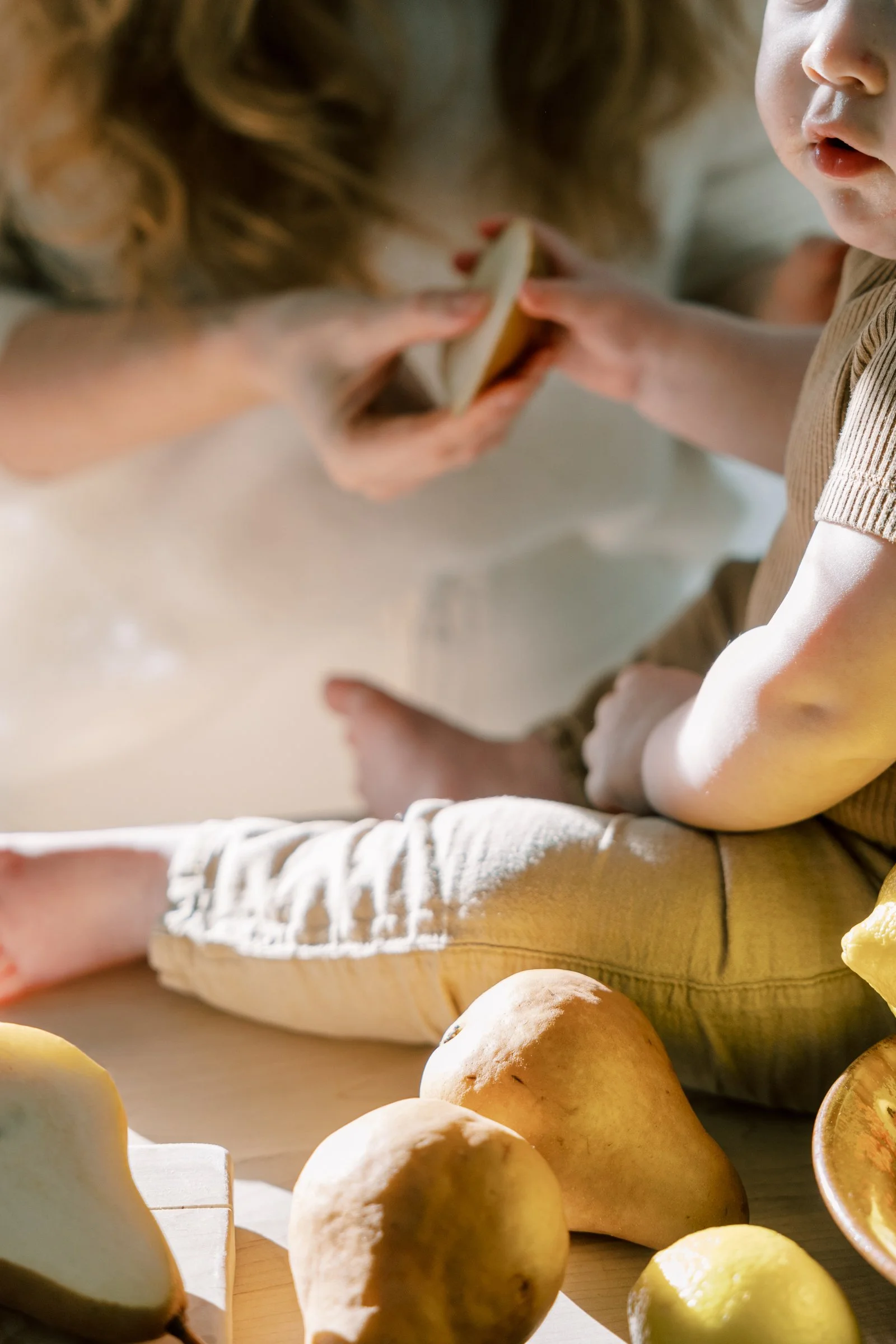 Close-up of children and adult making a snack, with potatoes and lemons on the table.