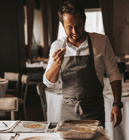 Male chef smiling and preparing food in a restaurant kitchen.