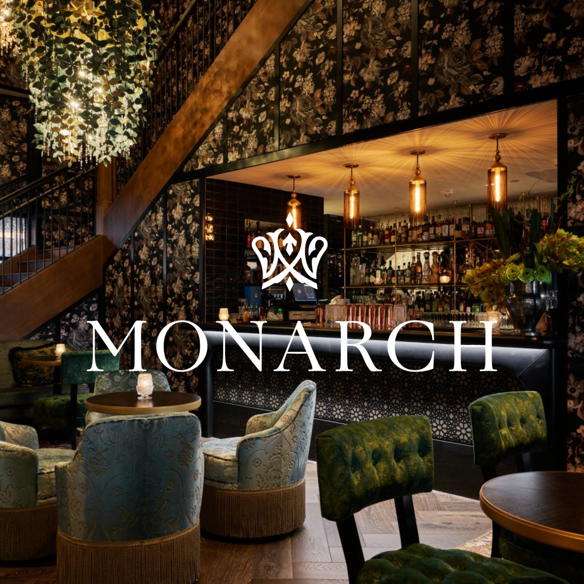 Interior of a restaurant with patterned wallpaper, blue upholstered chairs, and warm lighting fixtures.