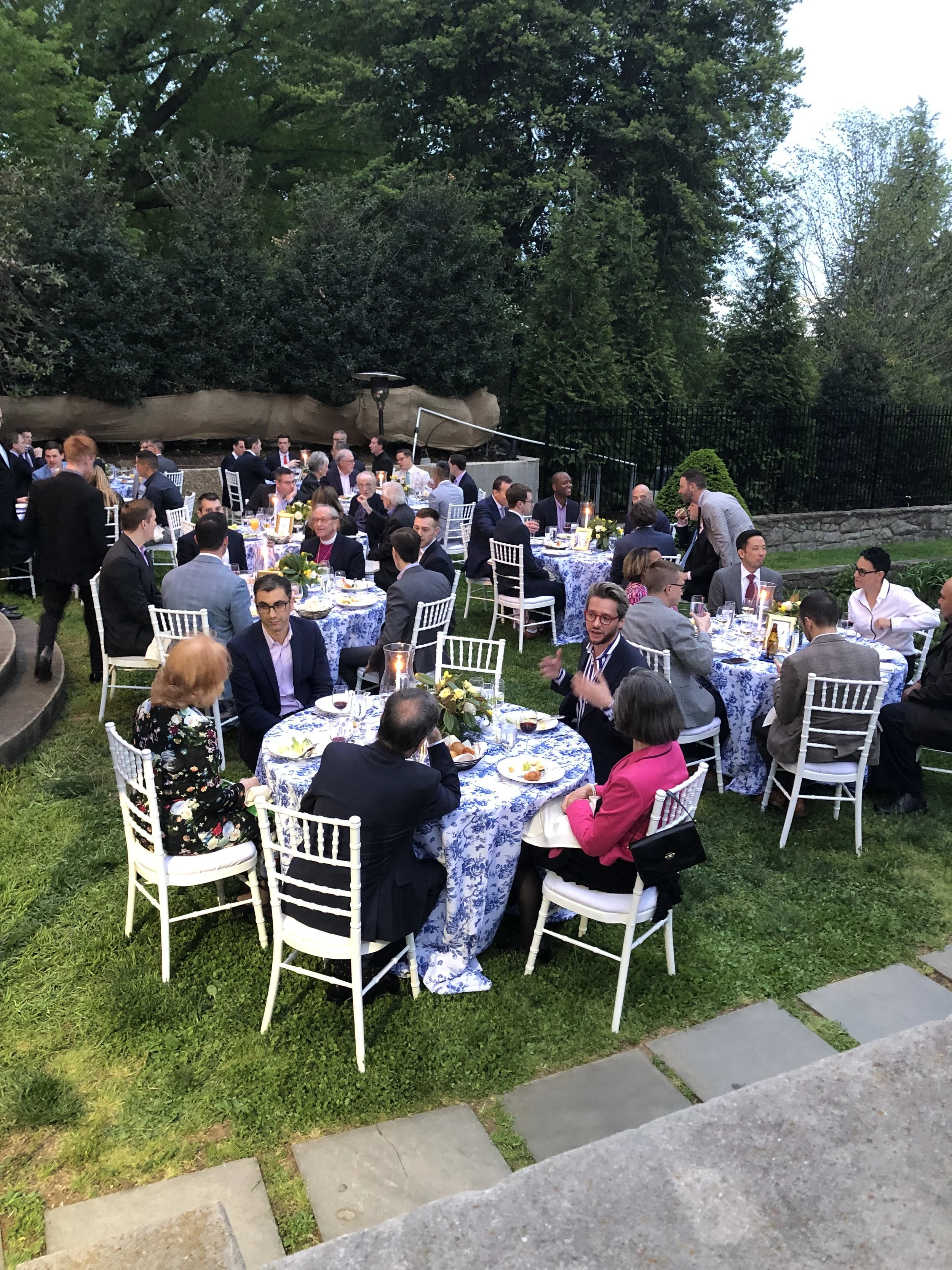 Nonprofit leaders and philanthropists in conversation at round tables during an outdoor evening dinner.