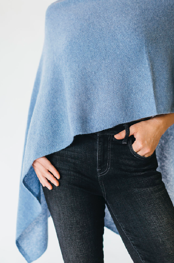 Person wearing dark jeans and a blue poncho, with one hand in pocket.