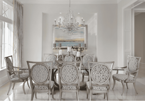 Elegant dining room with a large oval table, twelve upholstered chairs, a chandelier, and a large mirror on the wall.