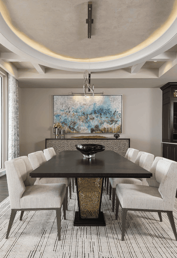 Modern dining room with a black rectangular table, eight beige upholstered chairs, a large abstract painting on the wall, and a decorative centerpiece on the table.