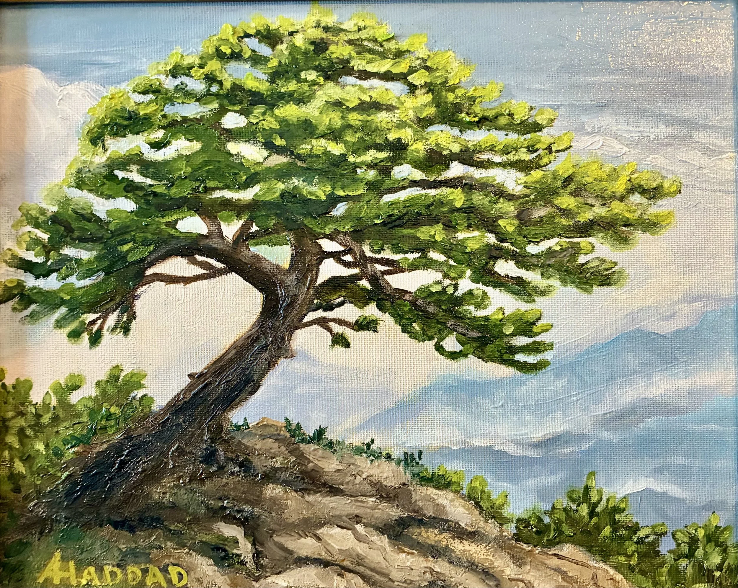Close-up of a painted landscape of a large, leafy tree with green foliage and brown trunk, set against a cloudy sky background, with partially visible text reading 'HADDAD' at the bottom.