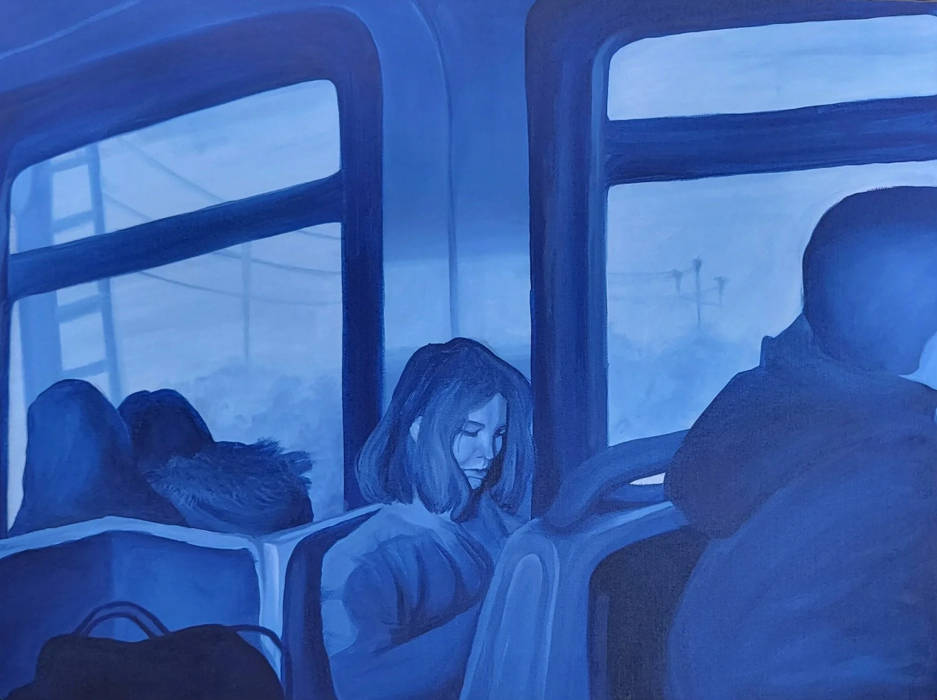 People sitting on a bus, with a woman with glasses and long hair looking down, and other passengers seated nearby.