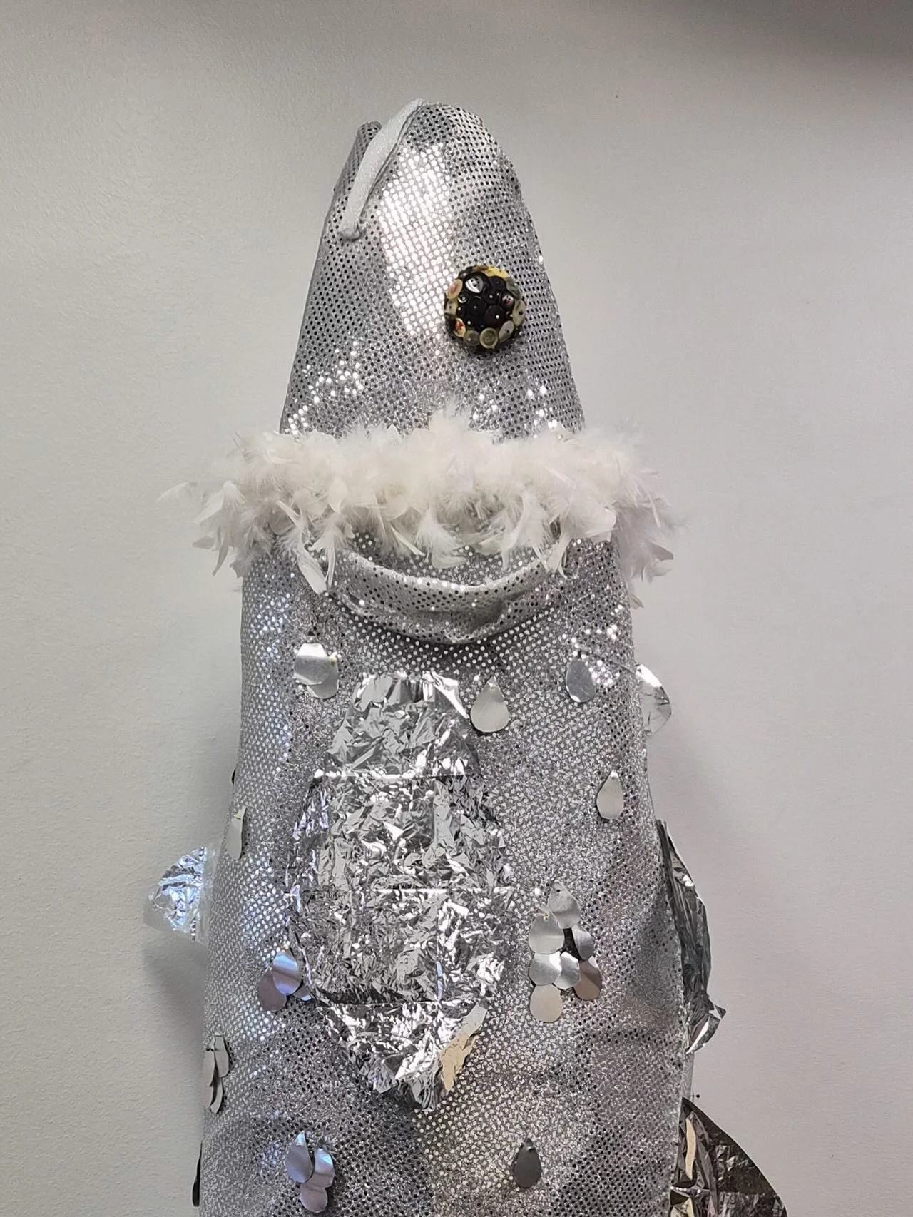 &ldquo;You are my Father as I am your Daughter&rdquo;, 2025
30in x 16in x 88in.
Metallic backdrop fabric, feather boa, fabric pins, buttons, aluminum scraps, metallic tissue paper, cardboard, newspaper, duct tape, and wire on a metal tripod.

This wo