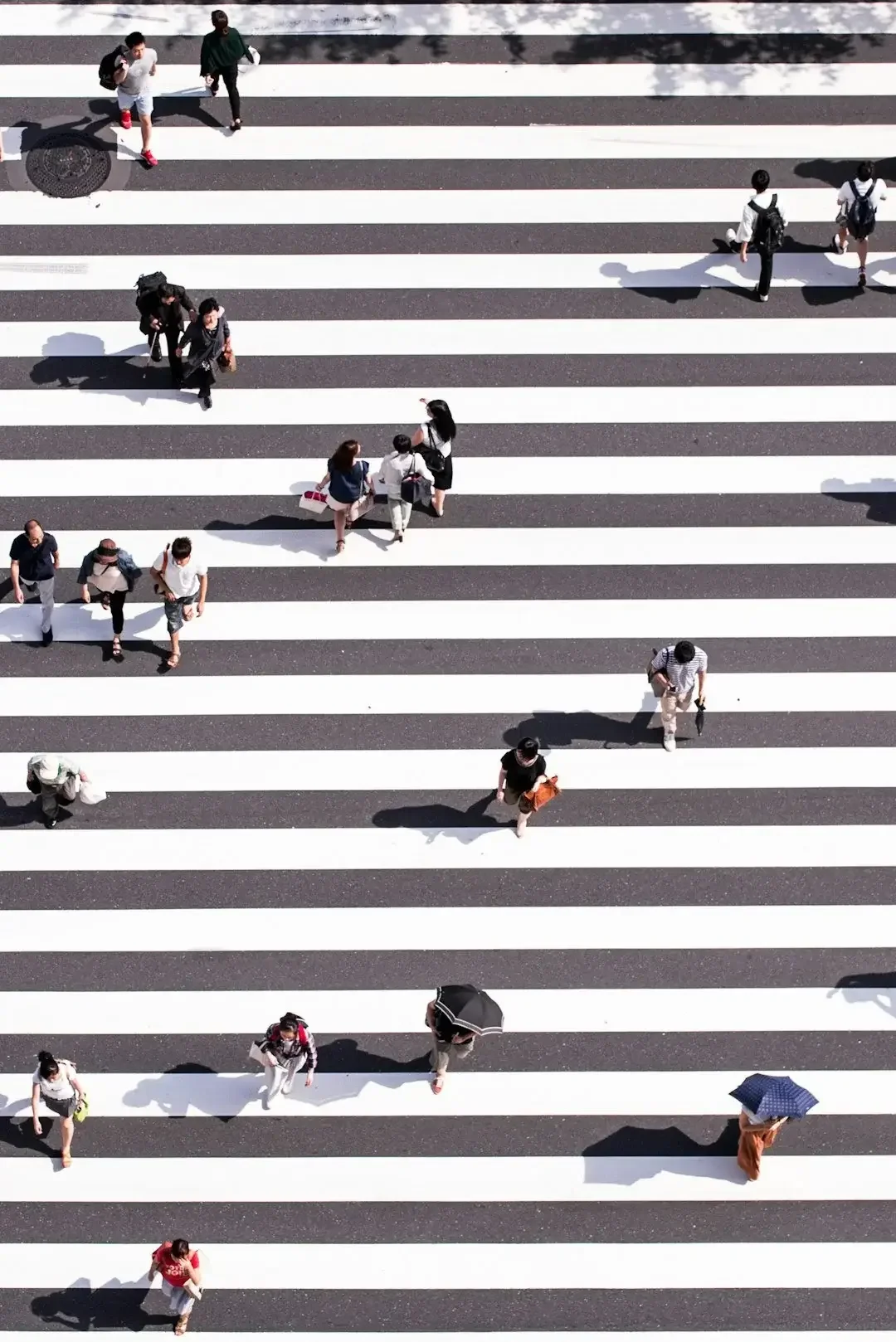 People walking across a zebra crossing on a city street.