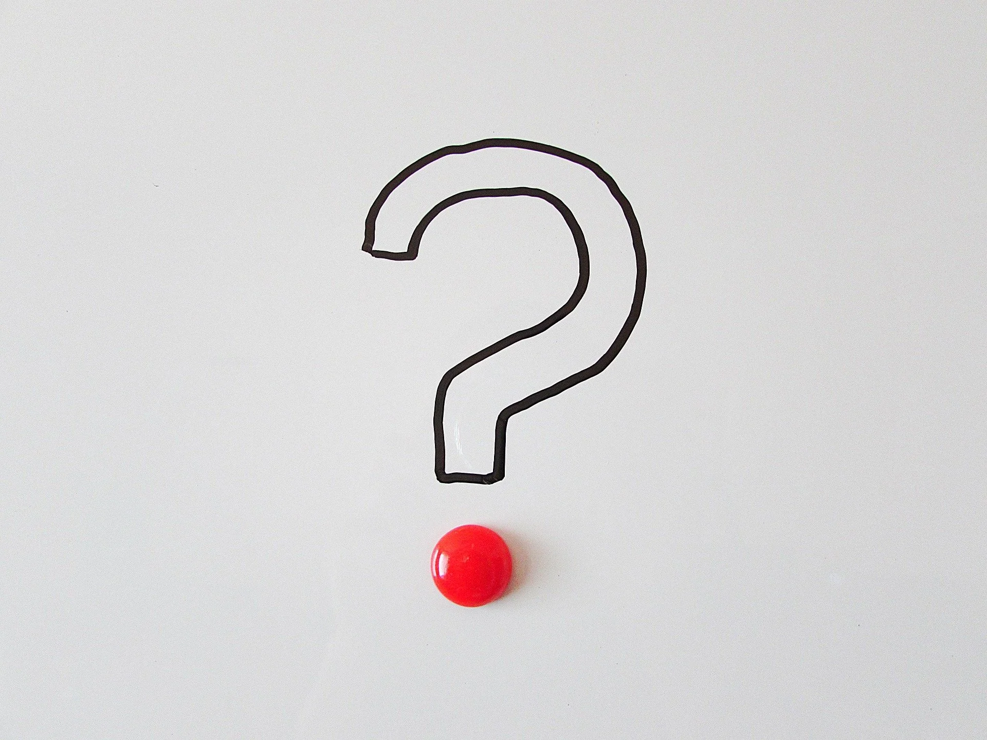 A white surface with a black outline drawing of a question mark, a red ball at the bottom center, and a black magnetic sphere at the top center.